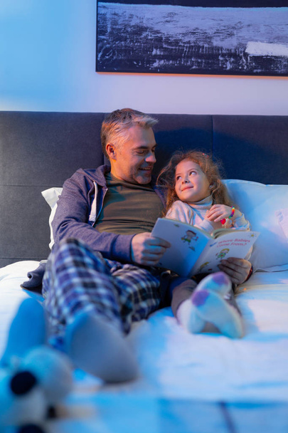 Grey-haired father spending an evening with his small pretty daughter - Foto, afbeelding