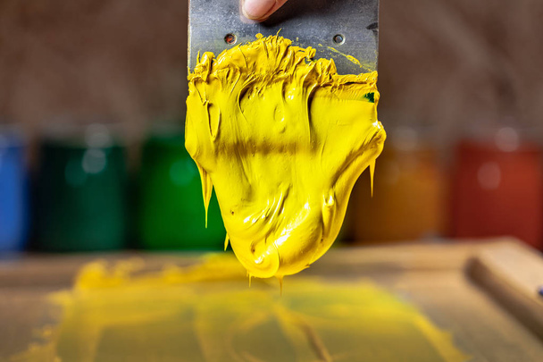 Gelbe Farbe tropft von Hand Siebdruck beim Drucken T-Shirt in T-Shirt Fabrik. - Foto, Bild
