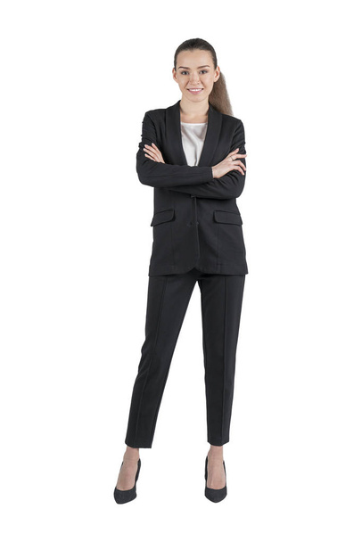 Isolated full length portrait of smiling young businesswoman with long fair hair wearing black suit and standing with crossed arms looking at camera - Foto, immagini