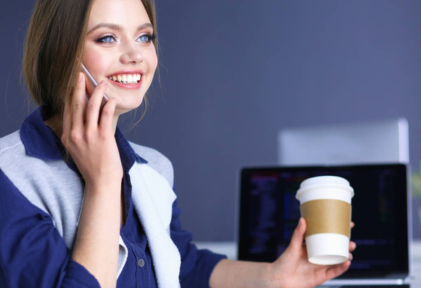 Fiatal boldog nő beszél a mobiltelefon, miközben ül egy csésze kávét - Fotó, kép