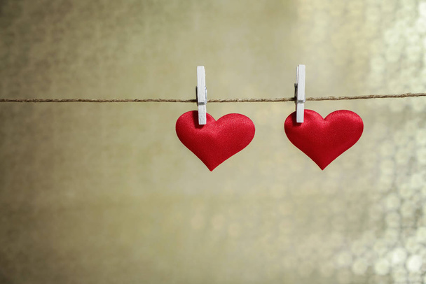 Twee schattige rode harten opknoping van een tekenreeks door witte kleren peg. Valentijnsdag of romantische gelegenheid met kopie ruimte - Foto, afbeelding
