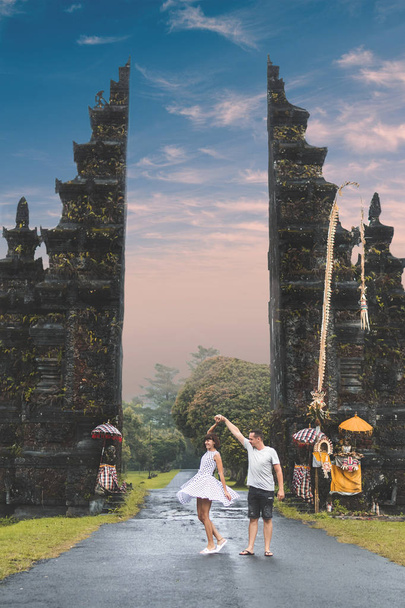 Ζευγάρι νεαρή μήνα του μέλιτος σε φόντο μεγάλο μπαλινέζικο πύλες. Νησί του Μπαλί, Ινδονησία. - Φωτογραφία, εικόνα