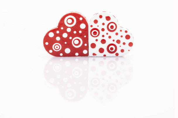 маленькие деревянные красные сердечки на белом с отражением
 - Фото, изображение