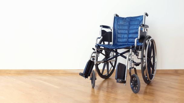 Empty blue wheelchair in a white room. - Foto, Bild