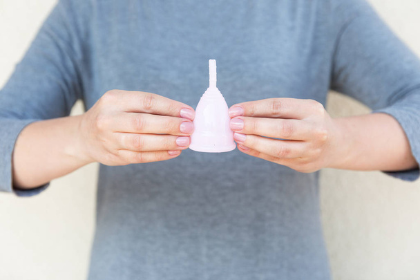 The menstrual cup is holding by woman hands. Selective focus. - Фото, зображення