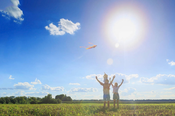 Familia feliz. Madre, padre e hija están volando una cometa en el campo. Vista frontal, espacio para copiar
. - Foto, imagen