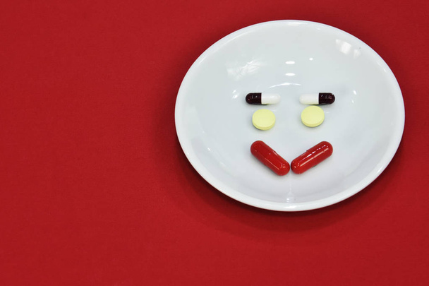 Happy face expression made of medicine. pain medication tablets. colored pills on porcelain dish. Assorted pharmaceutical pills. - Фото, изображение