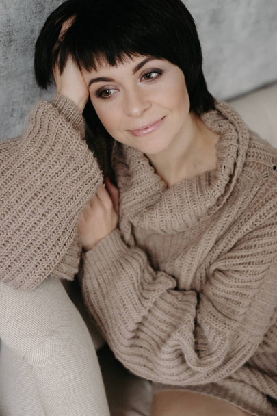 Splendida giovane donna bruna in caldo maglione a maglia in posa sul letto
 - Foto, immagini