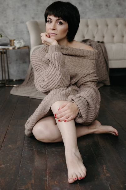 Hermosa joven morena en suéter de punto cálido posando en la cama
 - Foto, imagen