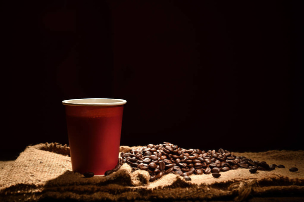 Papel taza de café y granos de café sobre fondo negro
 - Foto, imagen