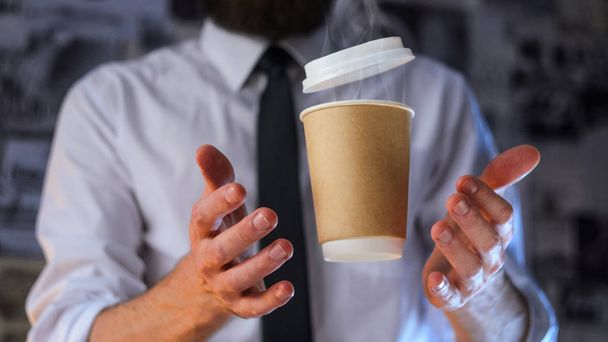 Barista, a bearded young man in a white shirt with a tie trying to catch a paper cup with hot coffee. Background for advertising. Empty place to your logo placement - Foto, afbeelding