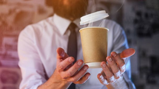 Barista in a white shirt with a tie holds floating in the air a paper cup with a hot drink on his outstretched arms. Barista wizard concept. Background for advertising and placing logo on your drink - Foto, Bild