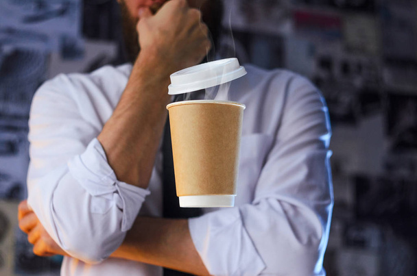 Meditative barista in a white shirt and tie and levitating paper cup of hot coffee. Background for advertising. Logo placement concept - Фото, зображення