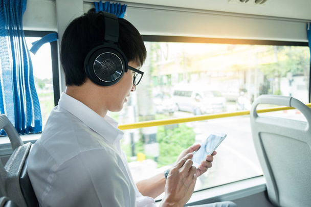Matkustajaliikenne. Ihmiset bussissa. mies ajaa bussilla, kuuntelee tai soittaa musiikkia ja kirjoittaa viestin ratsastaessaan kotiin
  - Valokuva, kuva