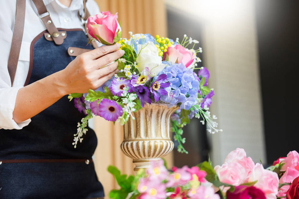 Female Florist at work using Arranging making beautiful Artificial bouquet vest at flower shop, business, sale and floristry craft and hand made concept - 写真・画像