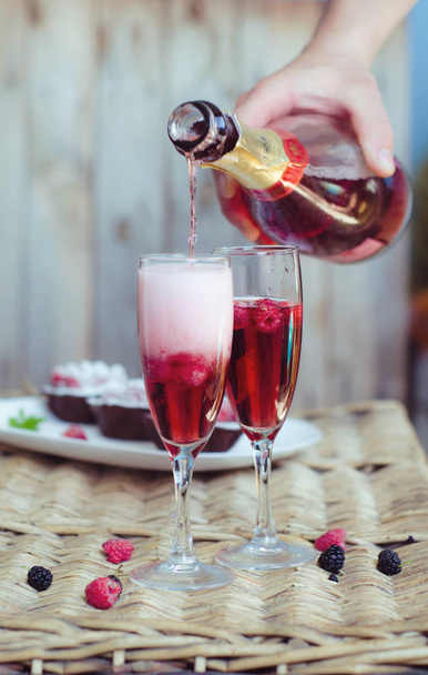 Κοκτέιλ σαμπάνιας για ένα κόμμα ή ένα ρομαντικό βράδυ σε ένα ξύλινο τραπέζι. Ροζ υγρό χρώμα, διαφανή ποτήρια με φυσαλίδες. Έννοια την ημέρα του Αγίου Βαλεντίνου - Φωτογραφία, εικόνα