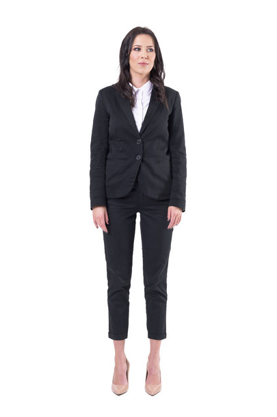 Successful young pretty business woman in black suit standing with arms down looking away. Full body isolated on white background.  - Fotografie, Obrázek