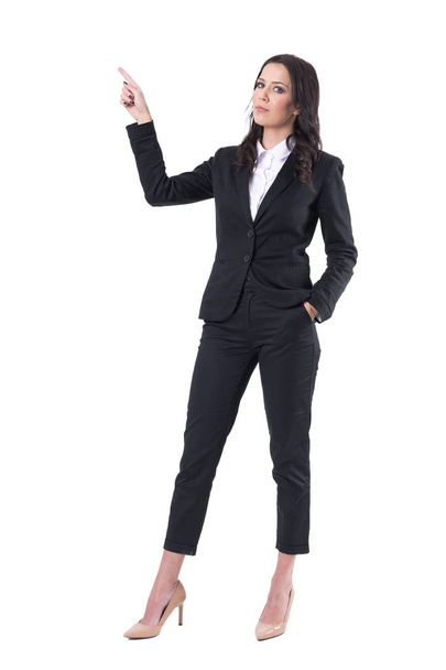 Grave donna d'affari fiduciosa che punta il dito verso l'alto facendo presentazione. Corpo intero isolato su sfondo bianco
.  - Foto, immagini