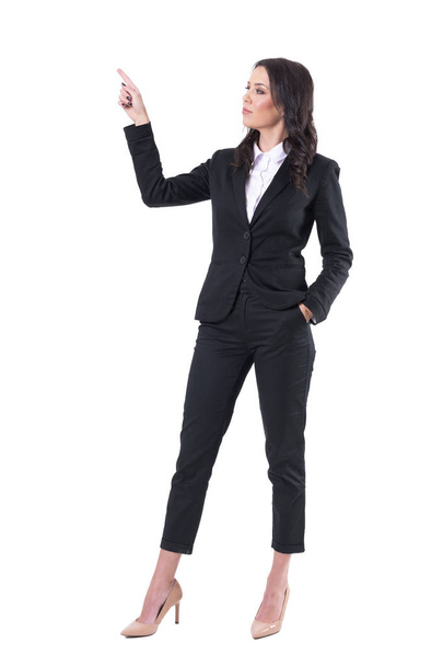 Elegante presentatrice donna d'affari in giacca e cravatta che punta il dito verso l'alto mostrando spazio per la copia. Corpo intero isolato su sfondo bianco
.  - Foto, immagini