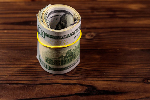 Role ze 100 dolarové bankovky na dřevěný stůl - Fotografie, Obrázek