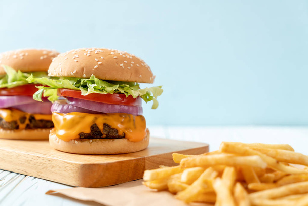 fresh tasty beef burger with cheese and french fries on wood background - Foto, afbeelding