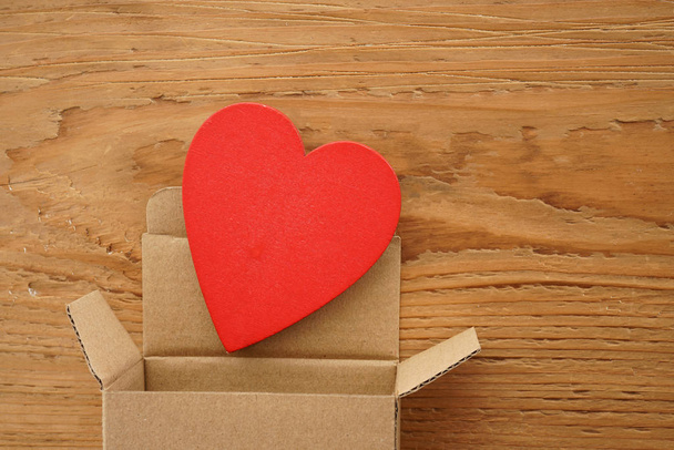 one red heart above open gift box on  wooden background. happy Valentines day. 14th february.                   - Фото, изображение