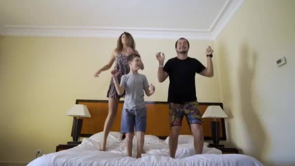 Familia feliz con hijo pequeño saltando en la cama en casa
 - Metraje, vídeo