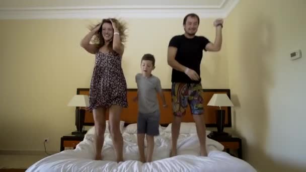 Feliz familia saltando sobre la cama. Concepto familiar feliz. Padre, madre y niño saltan a la cama
 - Metraje, vídeo
