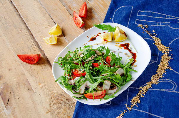 Свежий овощной салат с рукколой, грибами, помидорами в лимонно-медовом соусе на голубой салфетке. Концепция здорового питания. правильное питание
 - Фото, изображение