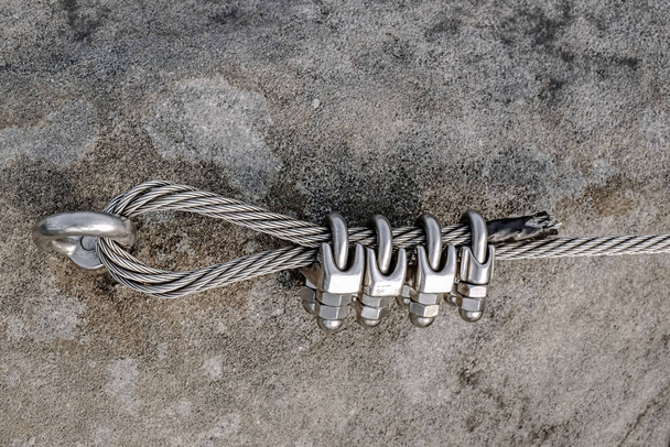 Stainless twisted rope anchored in rocky wall. Stair climbing and iron rope on mountain via ferrata - Photo, Image
