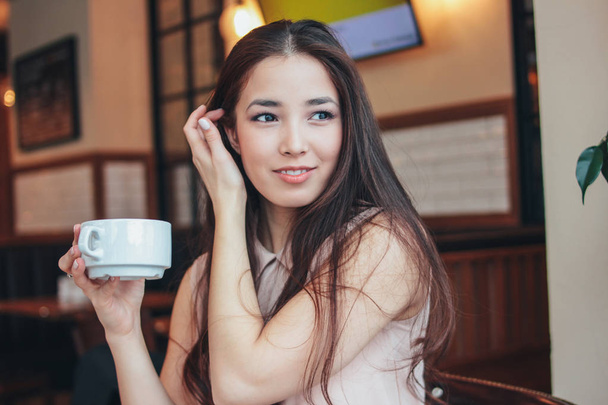 Linda morena romântica encantadora sorrindo menina asiática tem café da manhã com café no café
 - Foto, Imagem
