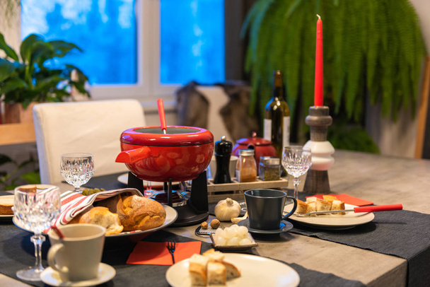 fondue de queijo suíço tradicional em um pote vermelho na mesa de jantar de concreto
. - Foto, Imagem