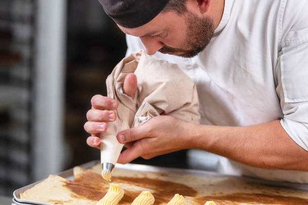 Pasticceria Chef con sacchetto pasticceria spremitura panna in pasticceria
. - Foto, immagini
