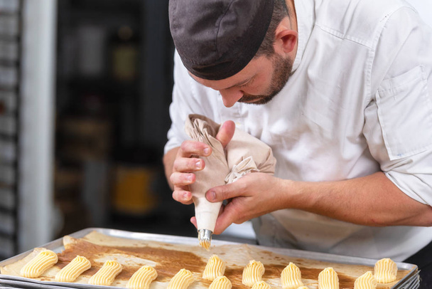 Pastelería Chef con bolsita de confitería exprimiendo crema en pastelería
. - Foto, Imagen