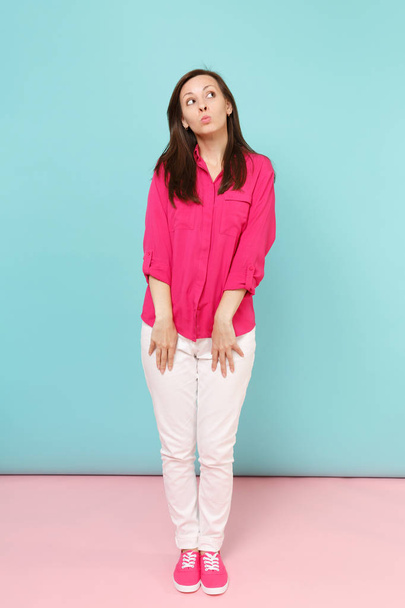 Retrato de larga duración de una joven y bonita mujer sonriente en blusa de camisa rosa, pantalones blancos posando aislados en un estudio de fondo de pared pastel azul rosado brillante. Concepto de estilo de vida. Simular espacio de copia
 - Foto, imagen