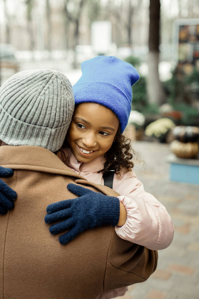 Padre con cappotto beige e cappello grigio che abbraccia la figlia minore
 - Foto, immagini