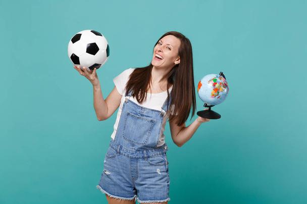 Γέλιο νεαρή γυναίκα ευθυμία ανεμιστήρας ποδοσφαίρου επάνω αγαπημένη ομάδα υποστήριξης με μπάλα ποδοσφαίρου, παγκόσμια σφαίρα που απομονώνονται σε μπλε φόντο τιρκουάζ. Άνθρωποι συναισθήματα, έννοια του αθλητισμού αναψυχής από την οικογένεια. Κοροϊδεύετε αντίγραφο χώρου - Φωτογραφία, εικόνα