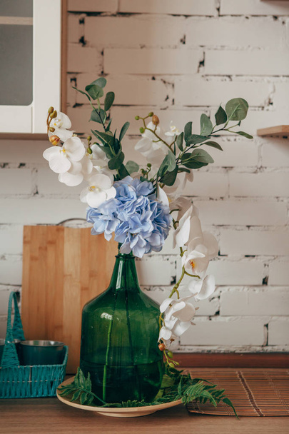 Kitchen interior: flowers in a green bottle on a table. Cozy home interior. - Φωτογραφία, εικόνα