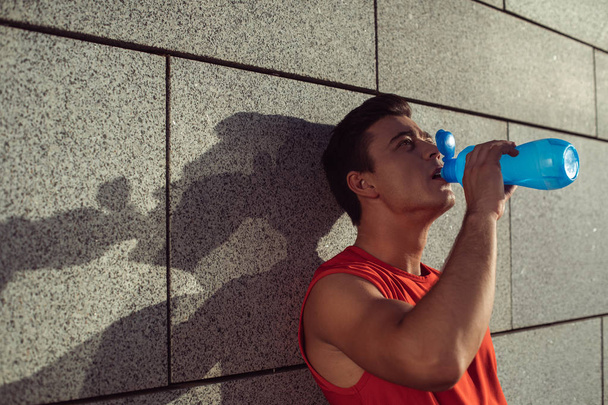 Serene man tasting delicious liquid after training - Фото, изображение