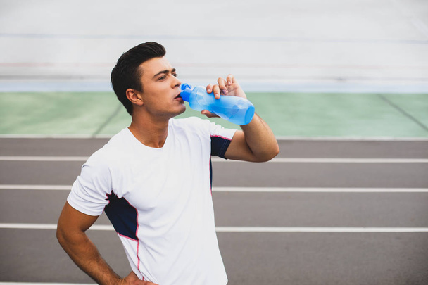 Focused male tasting beverage after workout outdoor - Photo, image