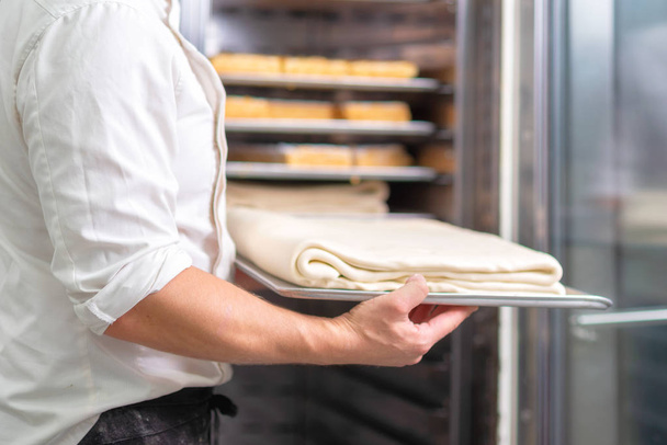 Chef de pastelaria, colocando a bandeja com massa na geladeira
. - Foto, Imagem