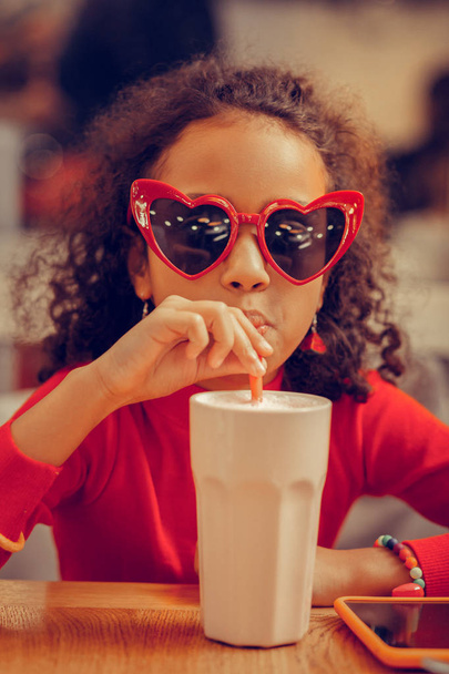 Chica linda divertida con gafas de sol rojas bebiendo batido
 - Foto, Imagen