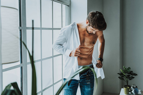 Young male wearing his shirt in morning - Foto, afbeelding