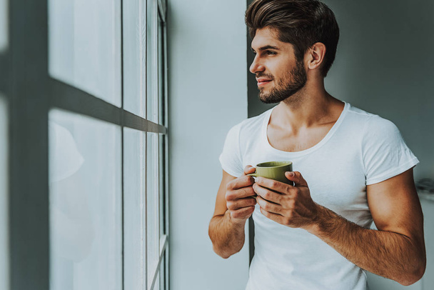 Young guy enjoy hot drink in morning - Foto, afbeelding