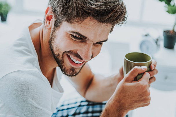 Smiling young guy drink coffee in morning - Φωτογραφία, εικόνα