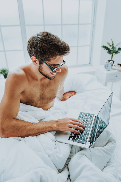 Happy male checking news on laptop early morning - Фото, зображення