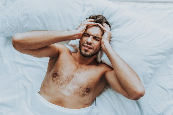 Young guy lay in bed with terrible head pain - Zdjęcie, obraz