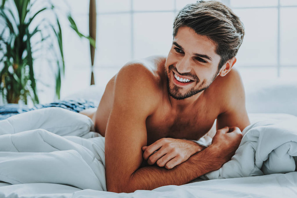 Šťastný attrective muž relaxační doma v posteli - Fotografie, Obrázek