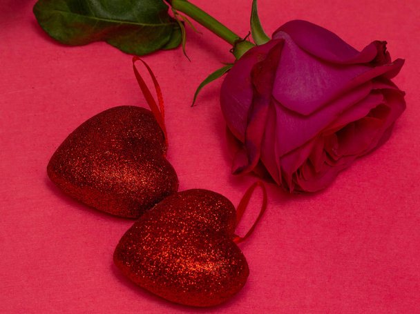 Virág rózsa-piros szív, egy rózsaszín háttér. Piros szív, egy rózsaszín háttér. St. Valentin nap gyönyörű háttér szívét. Szerelem és romantika fogalma. - Fotó, kép