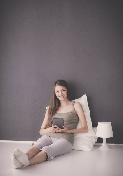 Pretty brunette woman sitting on the floor with a pillow and plane table - Photo, Image